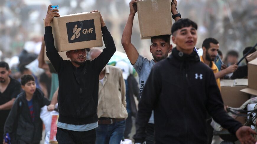 People carry supplies from a Gaza Humanitarian Foundation distribution centre in the central Gaza Strip