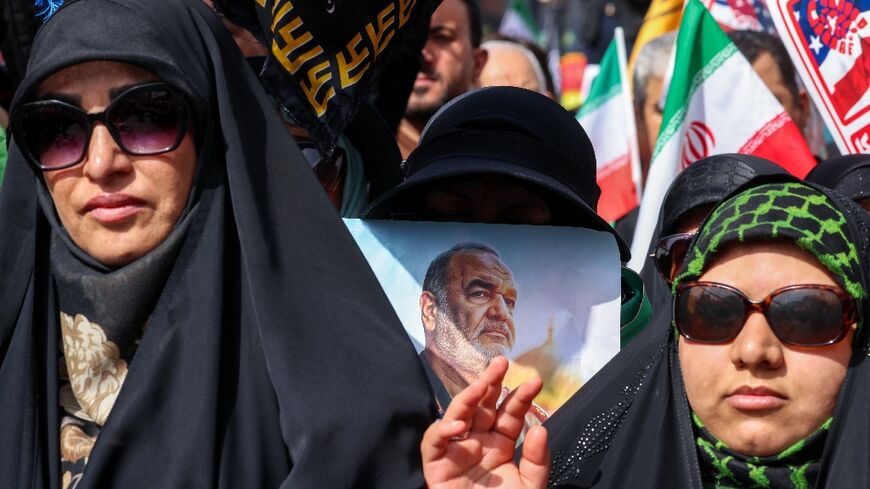 A woman holds a portrait of slain Iranian Revolutionary Guards commander Hossein Salami as mourners attend his funeral and that of other military commanders killed during Israeli strikes