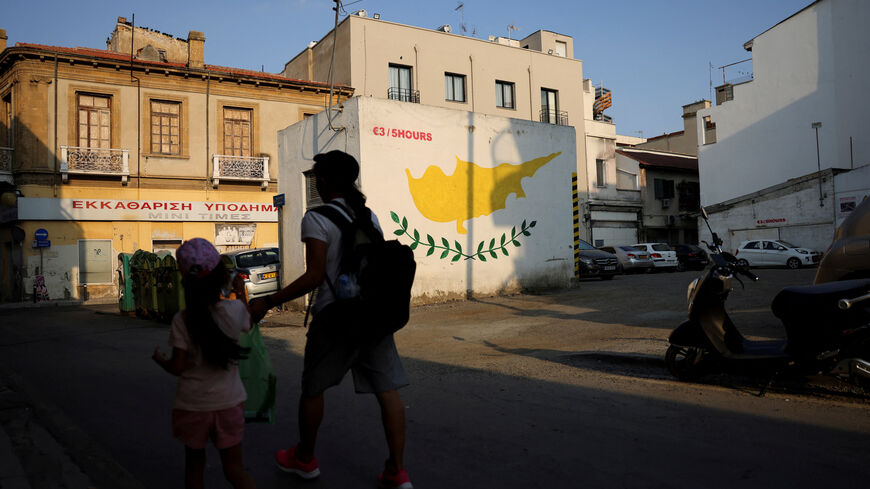 People walk next to a Cypriot flag painted on a wall in Nicosia, Cyprus July 17, 2025. REUTERS/Yiannis Kourtoglou