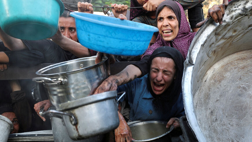 FILE PHOTO: Palestinians react as they ask for food from a charity kitchen, amid a hunger crisis, in Gaza City, July 14, 2025. REUTERS/Mahmoud Issa/File Photo