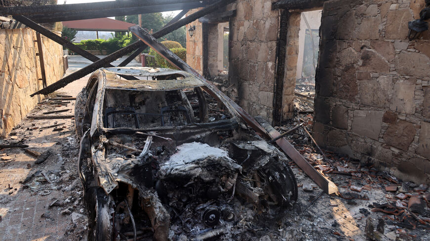 A burnt car is seen, as a wildfire burns in the village of Souni, near Limassol, Cyprus July 24, 2025. REUTERS/Yiannis Kourtoglou