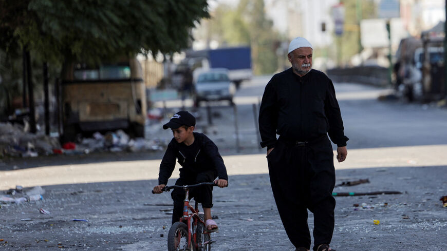 A man walks on a street, next to a child riding a bicycle, following deadly clashes between Druze fighters, Sunni Bedouin tribes and government forces, in Syria's predominantly Druze city of Sweida, Syria July 25, 2025. REUTERS/Khalil Ashawi/File Photo