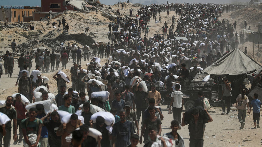 FILE PHOTO: Palestinians carry aid supplies that entered Gaza through Israel, in Beit Lahia, northern Gaza Strip, July 27, 2025. REUTERS/Mahmoud Issa/File Photo