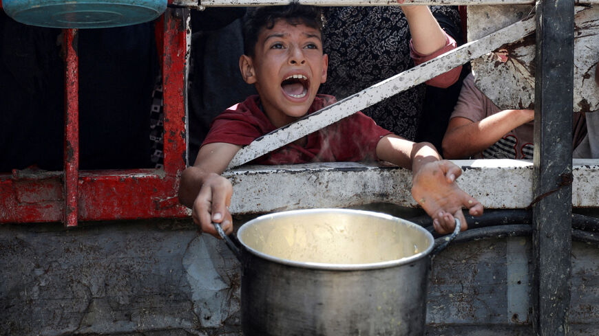 A Palestinian reacts as he waits to receive food from a charity kitchen, amid a hunger crisis, in Gaza City, July 28, 2025. REUTERS/Khamis Al-Rifi