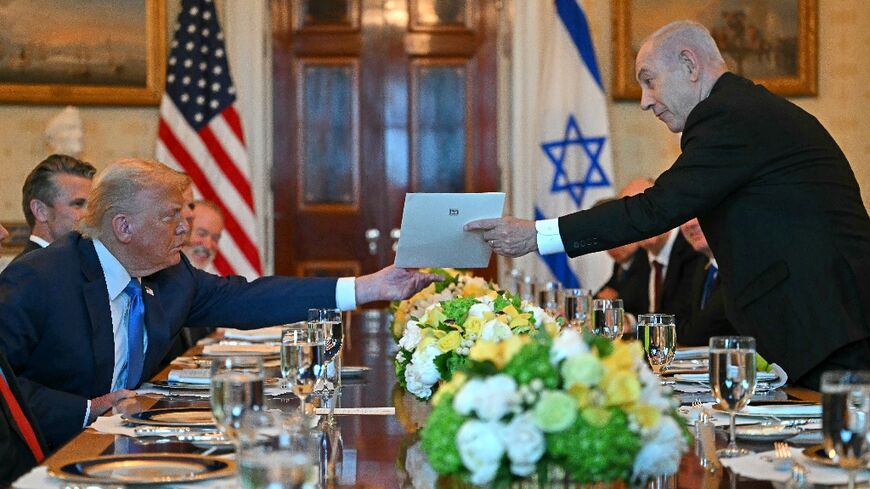 Israeli Prime Minister Benjamin Netanyahu hands over a letter to US President Donald Trump as they meet at the Blue Room of the White House 