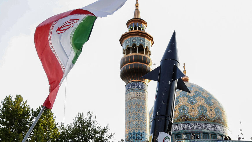 Iranians lift up a flag and the mock up of a missile during a celebration following Iran's missiles and drones attack on Israel, on April 15 2024, at Palestine square in central Tehran. Iran launched the attack on April 14, its first ever to directly target Israeli territory, in retaliation for a deadly air strike widely blamed on Israel that destroyed Tehran's consular building in Syria's capital early this month. (Photo by ATTA KENARE / AFP) (Photo by ATTA KENARE/AFP via Getty Images)