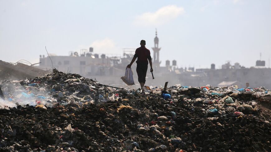 A Palestinian man searches for things to rescue at a garbage waste dump in the Al-Bureij camp in the central Gaza Strip on July 7, 2025.