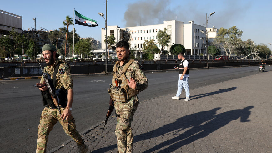 Syrian security forces stand guard in front of the heavily damaged Syrian army and defense ministry headquarters complex in Damascus, following Israeli strikes on July 16, 2025.