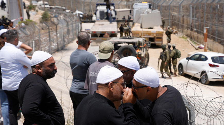 Druze men greet each other as they wait near the border fence in the town of Majdal Shams, in the Israeli-annexed Golan Heights, as Syrian Druze who had crossed over the day before to the village, cross back to return to Syrian, on July 17, 2025. Syrian government forces have withdrawn from the whole of Sweida province after days of sectarian bloodshed in the heartland of the Druze minority, a war monitor and witnesses said July 17, 2025. (Photo by Jalaa MAREY / AFP) (Photo