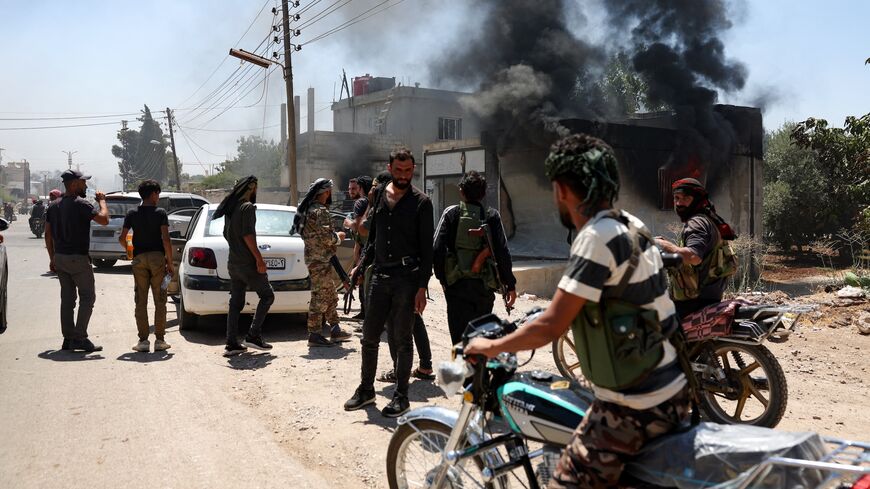 Fighters from Bedouin tribes gather near a burning building in al-Mazraa village, in Syria's southern Suwayda governorate, as clashes with Druze gunmen continue, on July 18, 2025. 