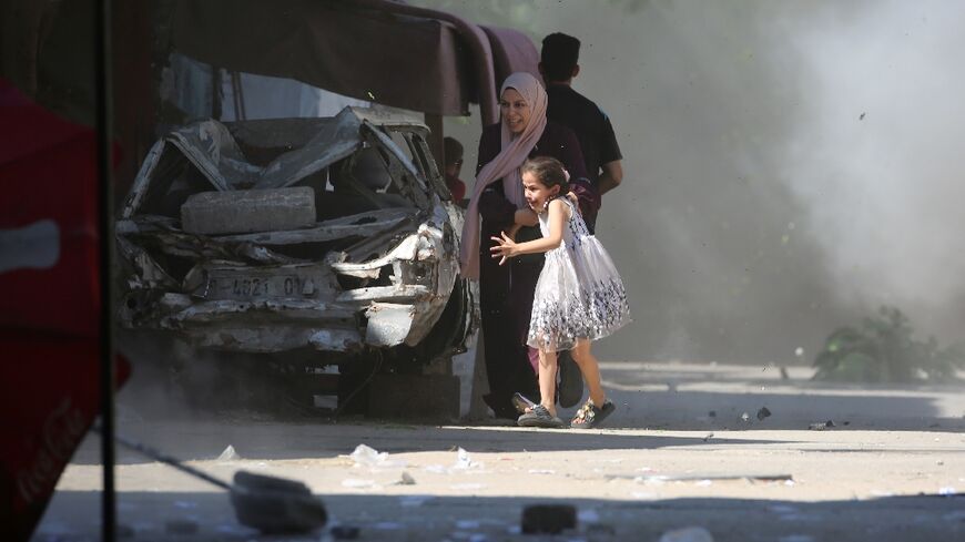 A Palestinian mother and her daughter rush for cover during an Israeli strike on Al-Bureij refugee camp in the central Gaza Strip.