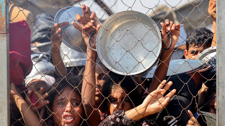 Palestinians, mostly children, push to receive a hot meal at a charity kitchen in the Mawasi area of Khan Yunis in the southern Gaza Strip on July 22, 2025