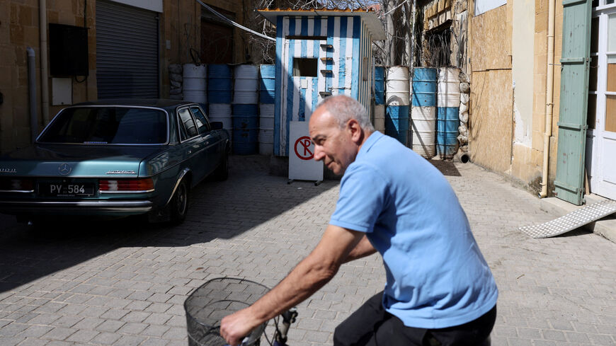 FILE PHOTO: A man rides a bicycle next to a barricade made of barrels at the UN-controlled buffer zone in Nicosia, Cyprus March 18, 2025.  REUTERS/Yiannis Kourtoglou/File Photo
