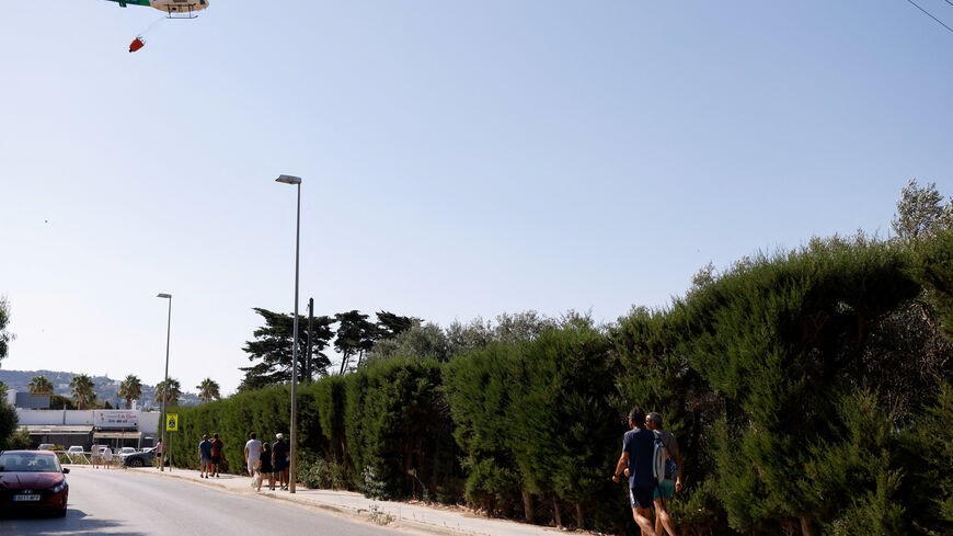 Locals and tourists walk back to their houses and hotels a day after they were evacuated from the Spanish town of Tarifa due to wildfires, in Tarifa, Spain, August 12, 2025. REUTERS/Marcelo Del Pozo