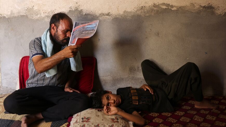 An Iraqi man fans his son at his home south of Hilla amid the heat of August