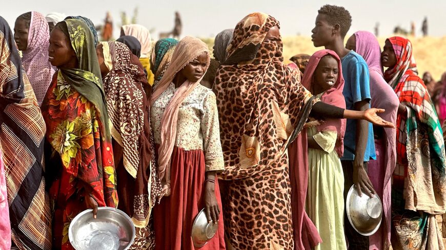 People who fled the Zamzam camp for the internally displaced after it fell under RSF control queue for food rations in a makeshift encampment in an open field near the town of Tawila in Sudan's western Darfur region on April 13, 2025.