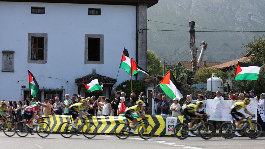 Cycling - Vuelta a Espana - Stage 13 - Cabezon de la Sal to L'angliru - Cantabria, Spain - September 5, 2025  Riders pass protesters with Palestine flags during stage 13 REUTERS/Pankra Nieto