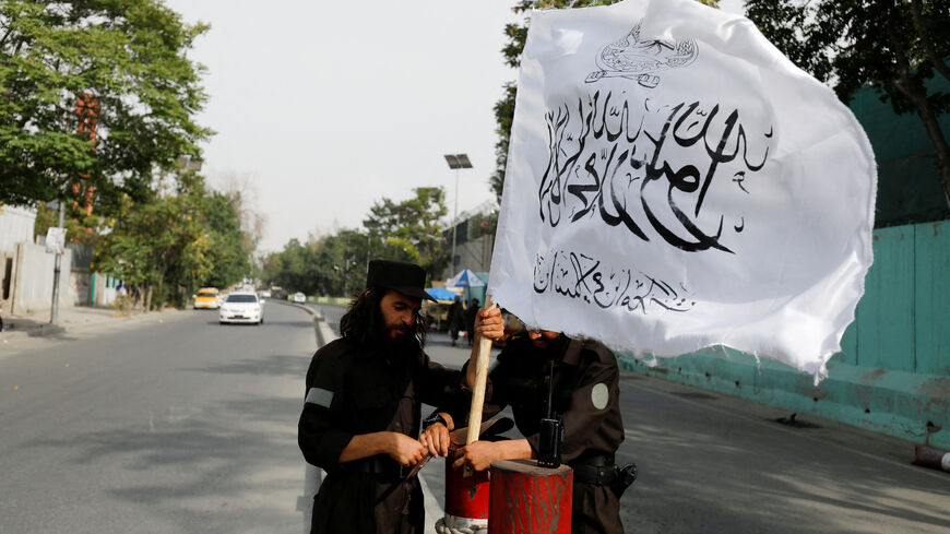 FILE PHOTO: Taliban fighters install a Taliban flag on a checkpoint in Kabul, Afghanistan, July 21, 2022. REUTERS/Ali Khara/File Photo