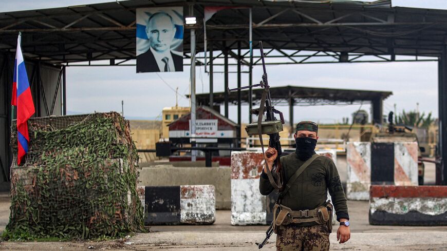 A Syrian rebel fighter looks on as he stands at an inspection checkpoint for incoming vehicles at the entrance of the Russian-leased Syrian military base of Hmeimim in Latakia province in western Syria on Dec. 29, 2024.