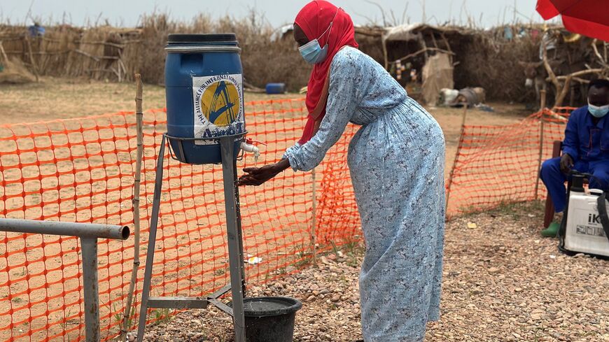 A woman washes her hands at the entrance of a cholera isolation center at the refugee camps of western Sudan, in Tawila in Darfur, on Aug. 12, 2025.