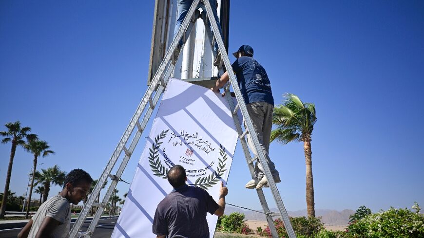 Municipal workers hang a sign advertising the upcoming US- and Egyptian-hosted Gaza peace summit in Sharm el-Sheikh