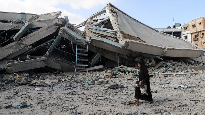 A Palestinian woman carries belongings as she walks amid debris at a United Nations school where displaced people were taking shelter, after it was hit in overnight Israeli strikes, amid an Israeli military operation, at Zeitoun neighbourhood in Gaza City, October 1, 2025. REUTERS/Ebrahim Hajjaj