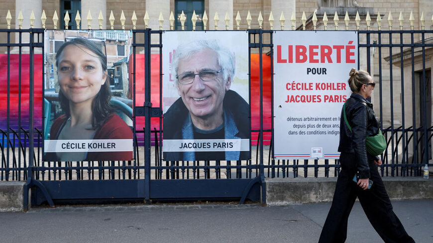FILE PHOTO: A woman walks past posters with the portraits of Cecile Kohler and Jacques Paris, two French citizens held in Iran, on the day of support rallies to mark their three-year detention and to demand their release, in front of the National Assembly in Paris, France, May 7, 2025. The slogan reads "Freedom for Cecile Kohler and Jacques Paris". REUTERS/Abdul Saboor/File Photo