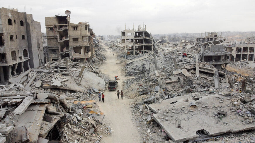 A drone view shows Palestinians walking past rubble following the withdrawal of the Israeli forces from the area, amid a ceasefire between Israel and Hamas in Gaza, in Gaza City, October 12, 2025. REUTERS/Dawoud Abu Alkas