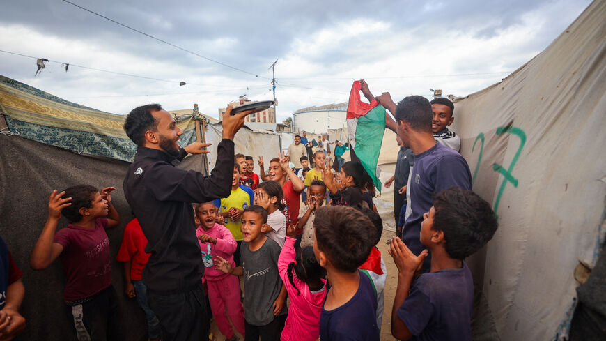 A man distributes sweets at a camp for displaced Palestinians in Nuseirat in the central Gaza Strip on Oct. 9, 2025, following news of a new Gaza ceasefire deal. 