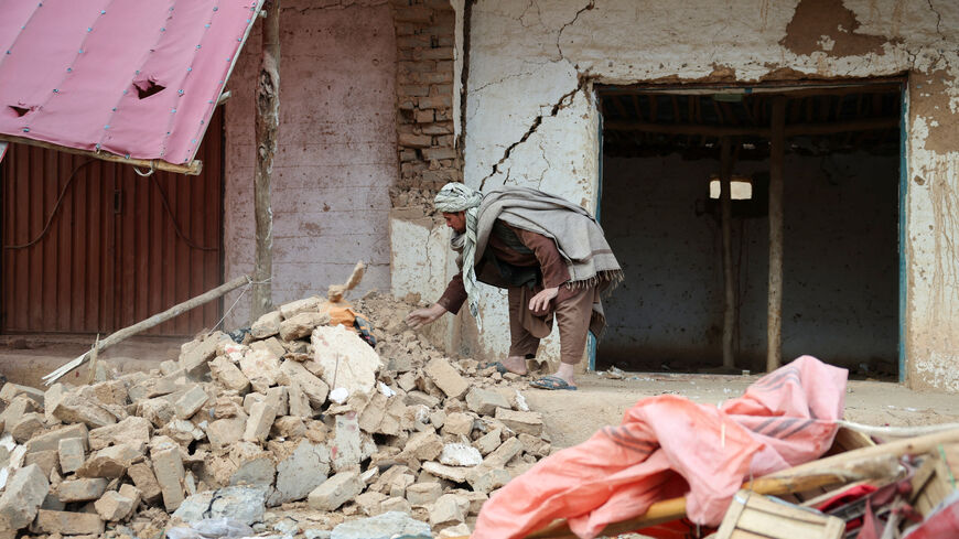A man remove debris next to damaged shops, in the aftermath of an earthquake, in Samangan province, Afghanistan, November 4, 2025. REUTERS/Sayed Hassib