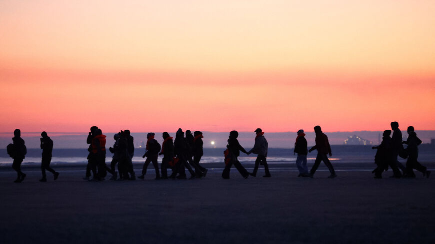 Migrants walk along the beach before trying to board an inflatable dinghy leaving the coast of northern France in an attempt to cross the English Channel to reach Britain, from the beach of Petit-Fort-Philippe in Gravelines, near Calais, France, September 27, 2025. REUTERS/Abdul Saboor