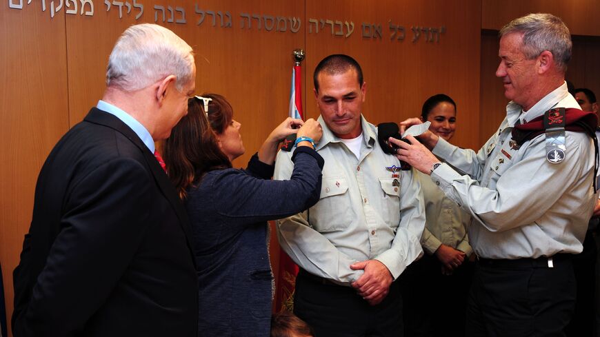 In this handout by the Israeli Government Press Office, Prime Minister Benjamin Netanyahu (L) looks on as military chief of staff Lt.-Gen. Benny Gantz (R) adjusts the epaulettes of Brig. Gen. Eyal Zamir for his swearing in as military secretary, Tel Aviv, Nov. 26, 2012.
