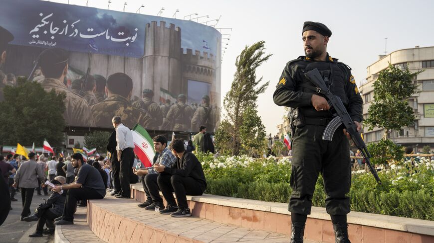 TEHRAN, IRAN - JUNE 24: A Police officer stands guard as demonstrators wave flags and cheer during a gathering to honor Iran’s military forces, following the announcement of a ceasefire between Israel and Iran, on June 24, 2025 in Tehran, Iran. Iranian authorities announced this morning they would agree to a ceasefire with Israel, whose attacks on Iran's military and nuclear sites on June 13 sparked a daily exchange of missiles between the countries. (Photo by Majid Saeedi/Getty Images)