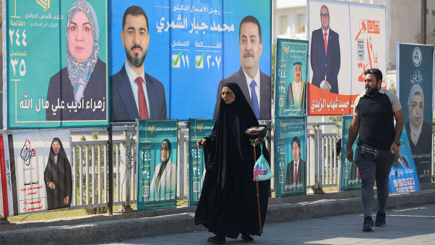 Iraqis walk past electoral billboards, including one bearing a portrait of Prime Minister Mohammed Shia al-Sudani (C), in central Baghdad on Oct. 19, 2025, ahead of Iraq's parliamentary elections on Nov. 11. 