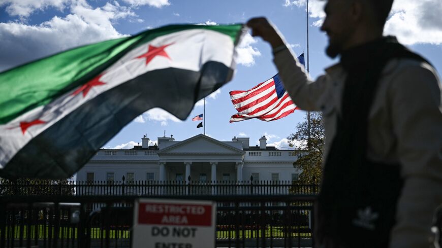 A man holds a Syrian flag across the street from the White House after Syrian President Ahmed al-Sharaa met with US President Donald Trump at White House in Washington on Nov. 10, 2025. 