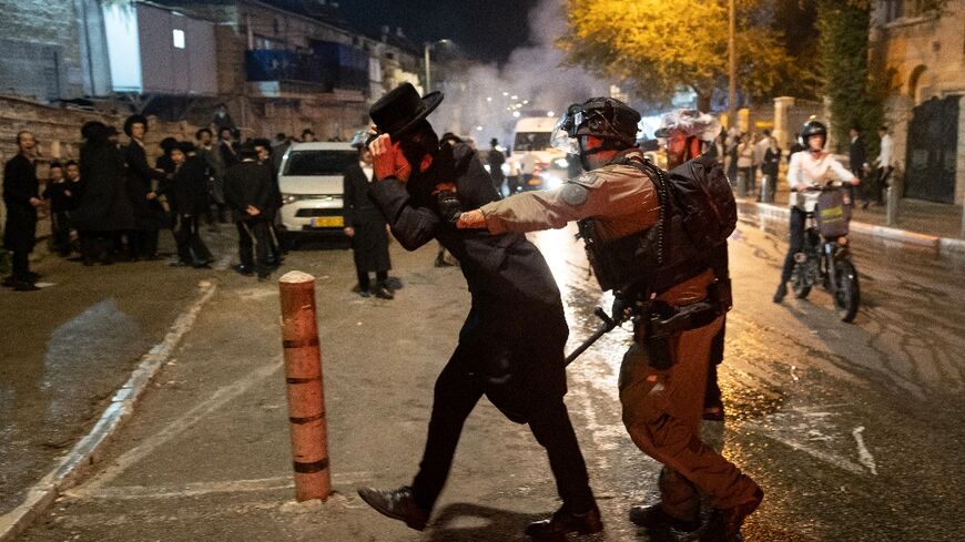 An Israeli police officer disperses an ultra-Orthodox Jewish demonstrator during a protest against conscription