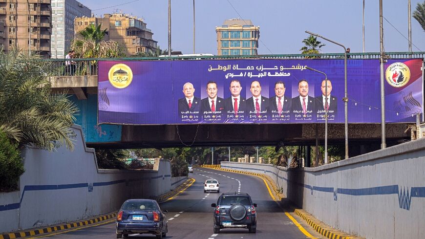 Motorists drive past a campaign billboard in Giza for the Egyptian parliamentary elections
