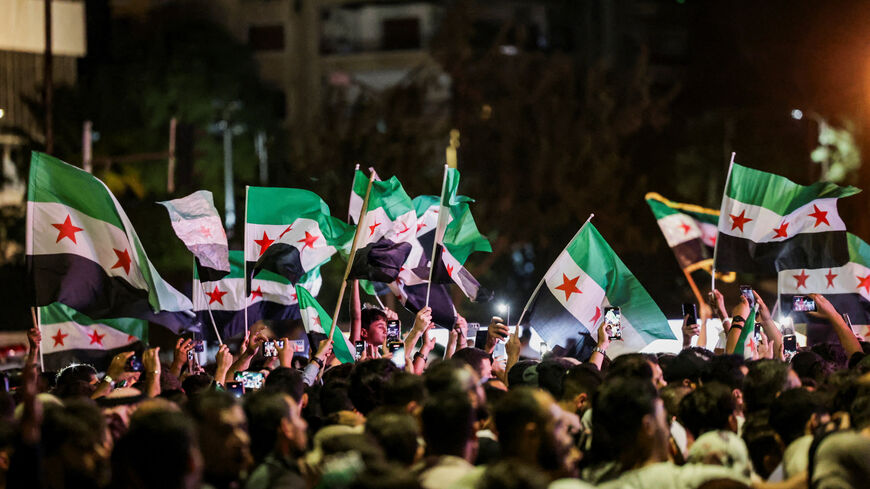 People wave Syrian flags as they gather at Umayyad Square in Damascus to watch a broadcast of Syrian President Ahmed Al-Sharaa delivering a speech at the United Nations, in Syria, September 24, 2025. REUTERS/Khalil Ashawi