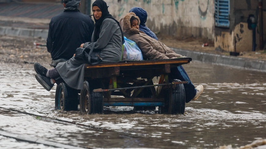 Displaced Palestinians make their way through a flooded street on a cart, during a rainy day in Nuseirat, central Gaza Strip, December 11, 2025. REUTERS/Mahmoud Issa