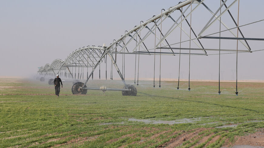 A farmer walks under a center-pivot irrigation system watering wheat fields in the desert of Basra, Iraq, November 27, 2025. Such projects aim to sustain crop production as Iraq faces one of its worst droughts in decades, with water levels in the Tigris and Euphrates rivers sharply down due to climate change and upstream restrictions. REUTERS/Mohammed Aty
