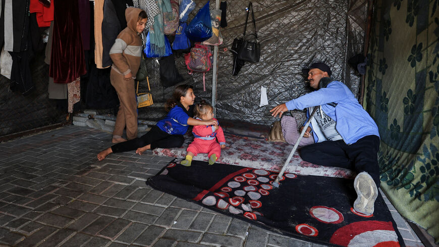 Displaced Palestinian Nihad Al-Ashqar sits inside his tent with his children after losing his source of income and becoming fully dependent on humanitarian assistance, in Gaza City, January 5, 2026. REUTERS/Dawoud Abu Alkas