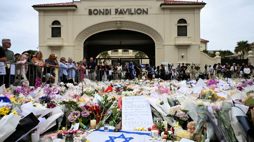 FILE PHOTO: People stand near flowers laid as a tribute at Bondi Beach to honour the victims of a mass shooting that targeted a Hanukkah celebration at Bondi Beach on Sunday, in Sydney, Australia, December 16, 2025. REUTERS/Flavio Brancaleone/File Photo