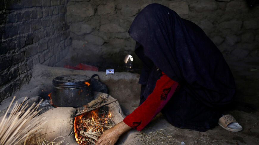 An Afghan woman lights fire to cook food at a makeshift kitchen in Markhor-e-Sufla village, Herat, Afghanistan October 26, 2024. REUTERS/Sayed Hassib