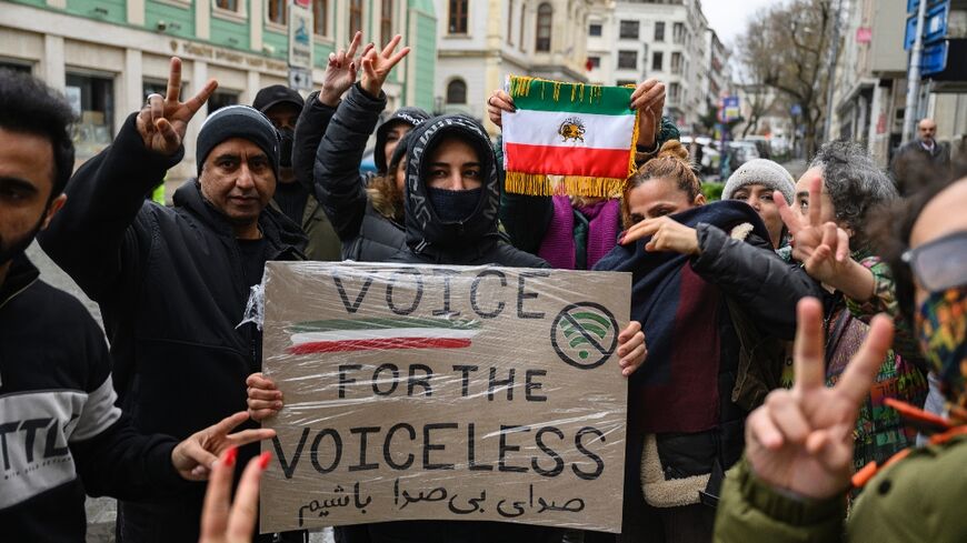 Protesters hold a placard reading "Voice for the voiceless" and the flag of Iran from before the 1979 revolution during a demonstration outside the Iranian Consulate in Istanbul