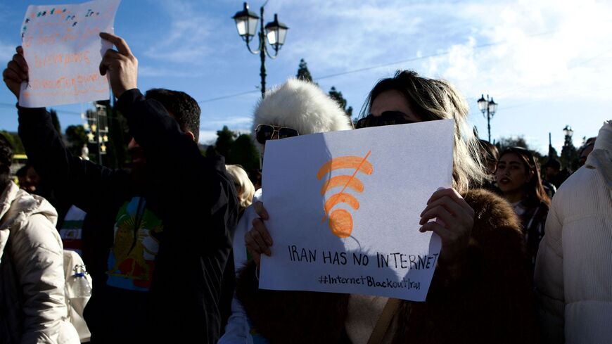 Backlit image of Iranian demonstrators holding national flags and portraits during an antiKhamenei protest at Syntagma Square in Athens, Greece, on January 11, 2026. What stands out is a woman holding a placard featuring a Wi Fi symbol and the message "Iran has no internet," referencing an internet blackout in Iran. The gathering takes place in front of the Hellenic Parliament, where protesters primarily supporters of the former Shah express opposition to the current Iranian regime and denounce restrictions