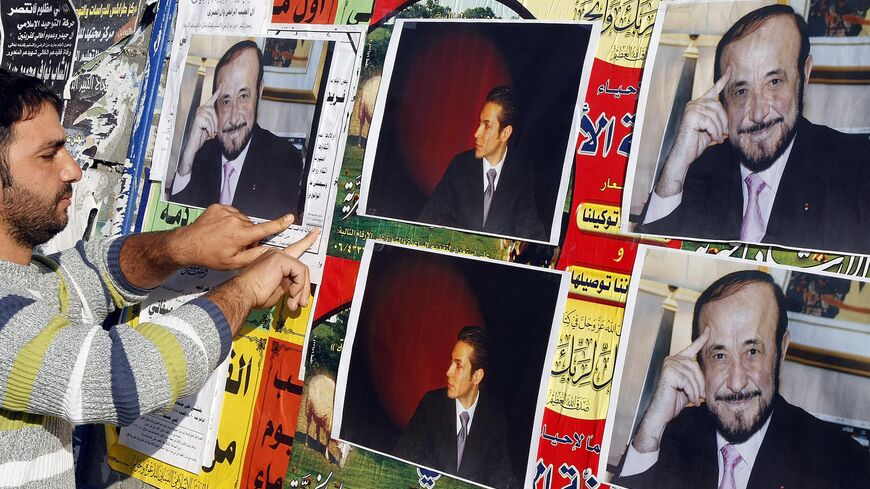 A member of the Alawite community pastes on a wall, in the northern Lebanese city of Tripoli , on December 6, 2007, pictures of Syrian opposition leader Rifaat al-Assad (R) and his son Ribal. 