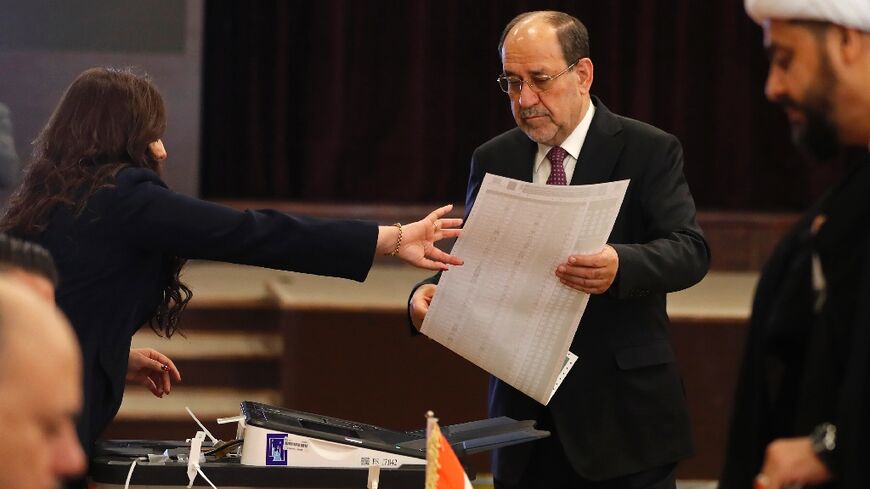 Former Iraqi prime minister Nouri al-Maliki holds the ballot paper at a polling station in Baghdad on November 11, 2025 during parliamentary elections
