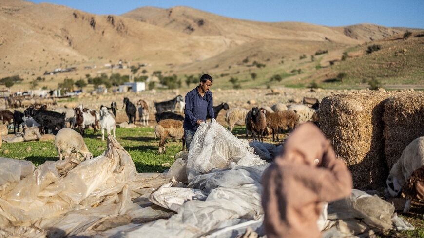 A Bedouin man gathers plastic sheeting as families begin to collect their belongings to leave their homes after harassment from Israeli settlers in Ras Ein al-Auja
