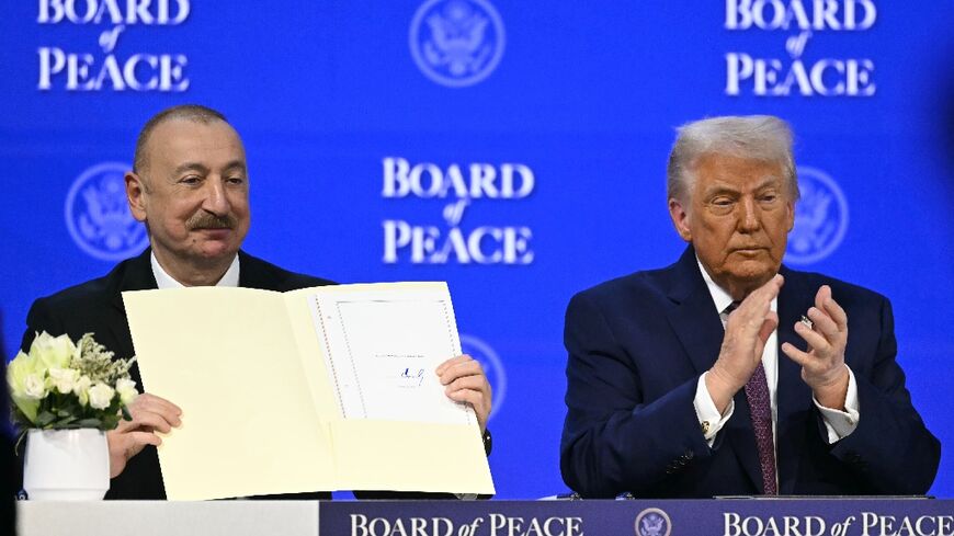Azerbaijan's President Ilham Aliyev holds a signed founding charter of the "Board of Peace" as US President Donald Trump applauds during the World Economic Forum in Davos, Switzerland