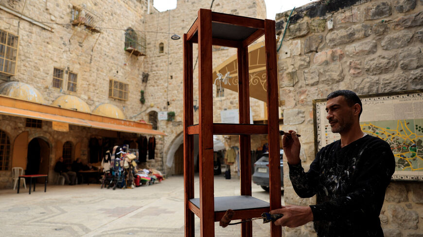 A Palestinian paints wood in the old city in Hebron in the Israeli-occupied West Bank, February 9, 2026. REUTERS/Mussa Qawasma